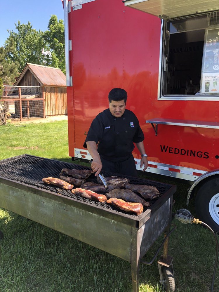 A Paisan's chef grilling tri-tip live beside the mobile kitchen during a wedding